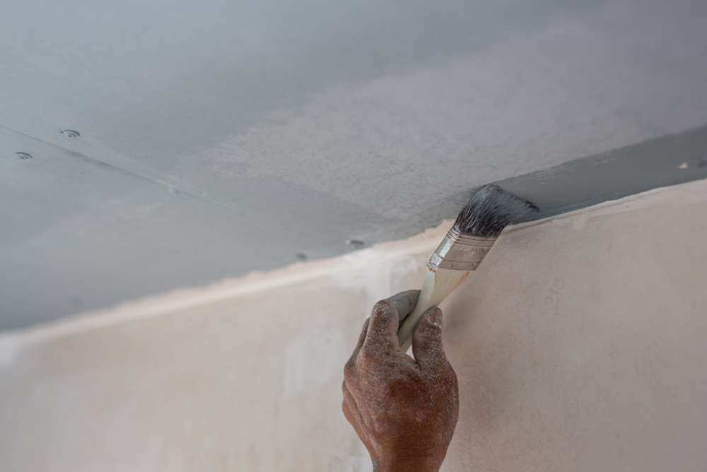 man priming drywall before painting